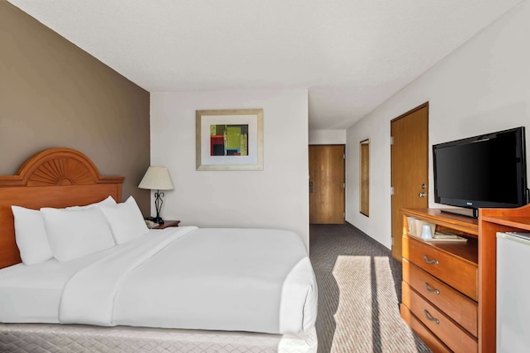A hotel room with a bed, a television, a dresser, and a framed picture on the wall.