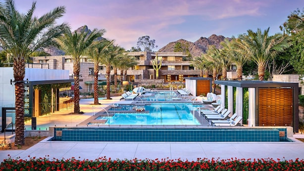 A pool area with lounge chairs, palm trees, and a mountain backdrop.
