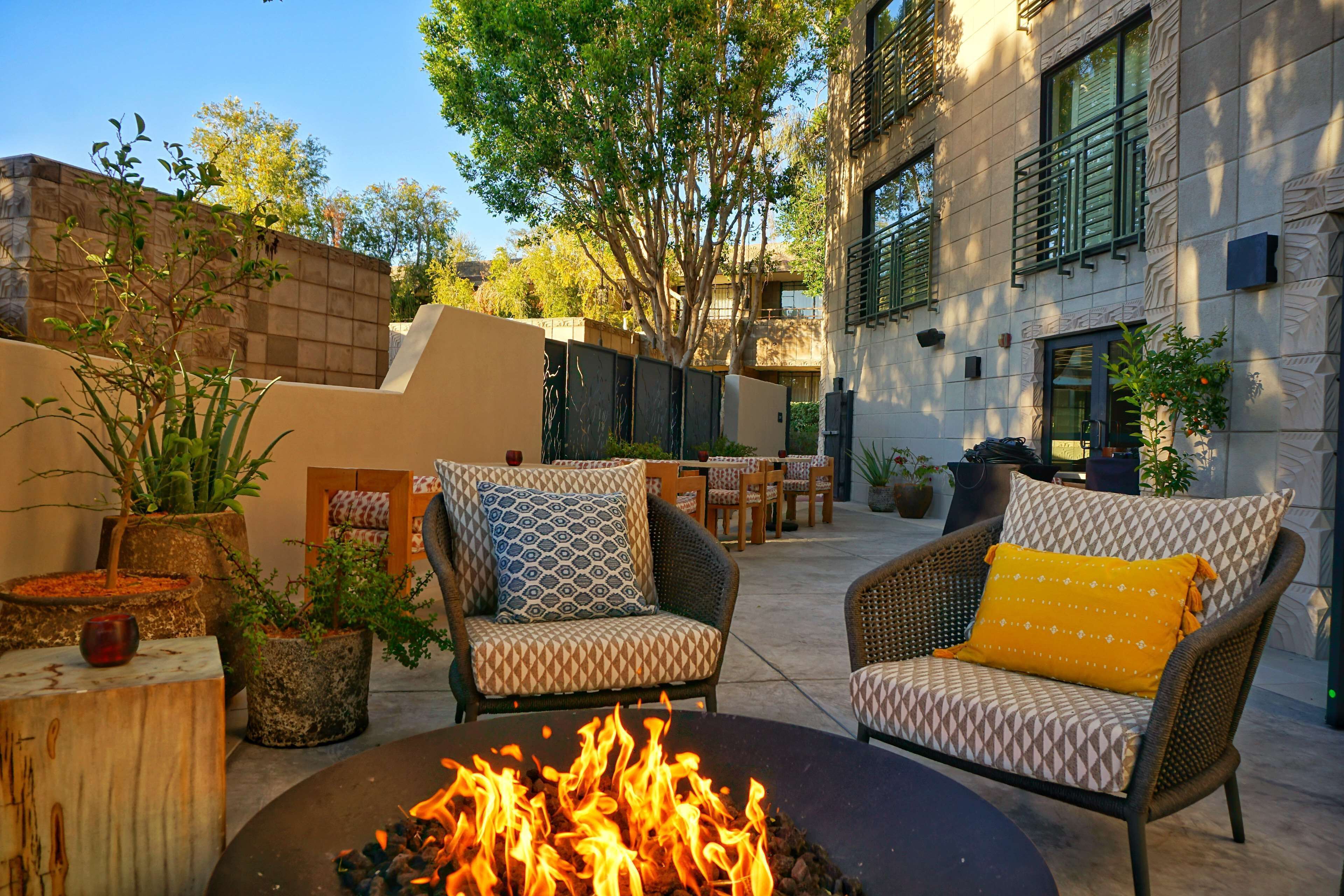 An outdoor seating area with two wicker chairs, a fire pit, and potted plants.