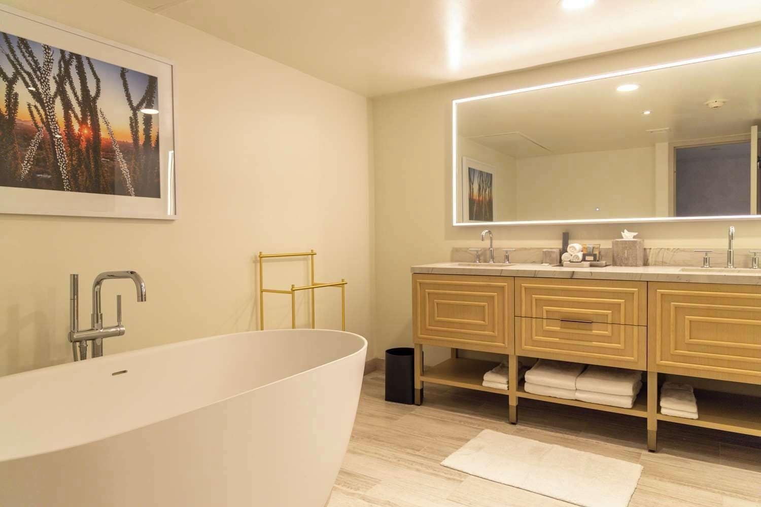 Une salle de bain moderne avec une baignoire sur pieds, un grand miroir et un meuble-lavabo en bois doté de deux vasques.