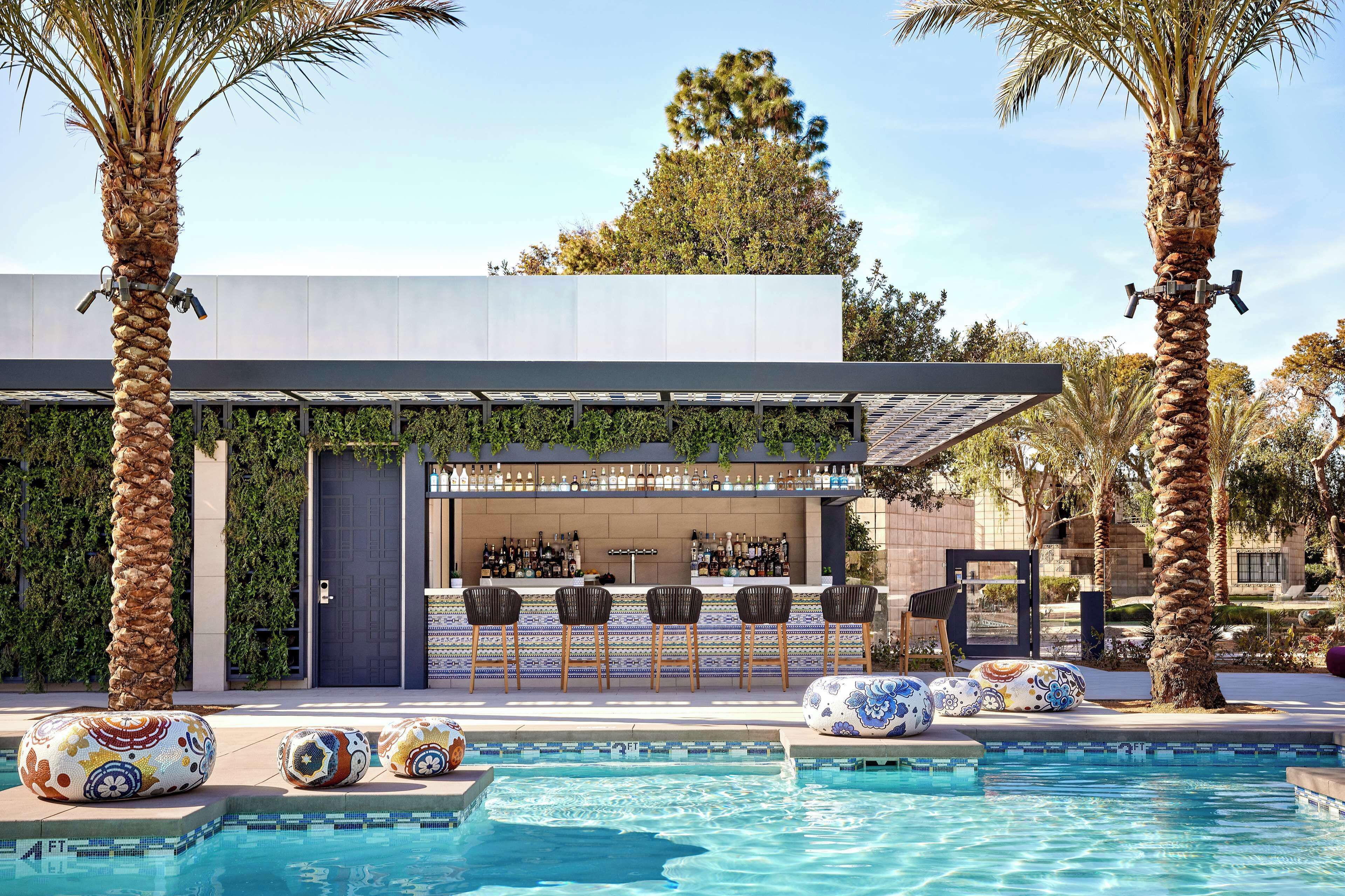 A pool area with a bar, lounge chairs, and palm trees.