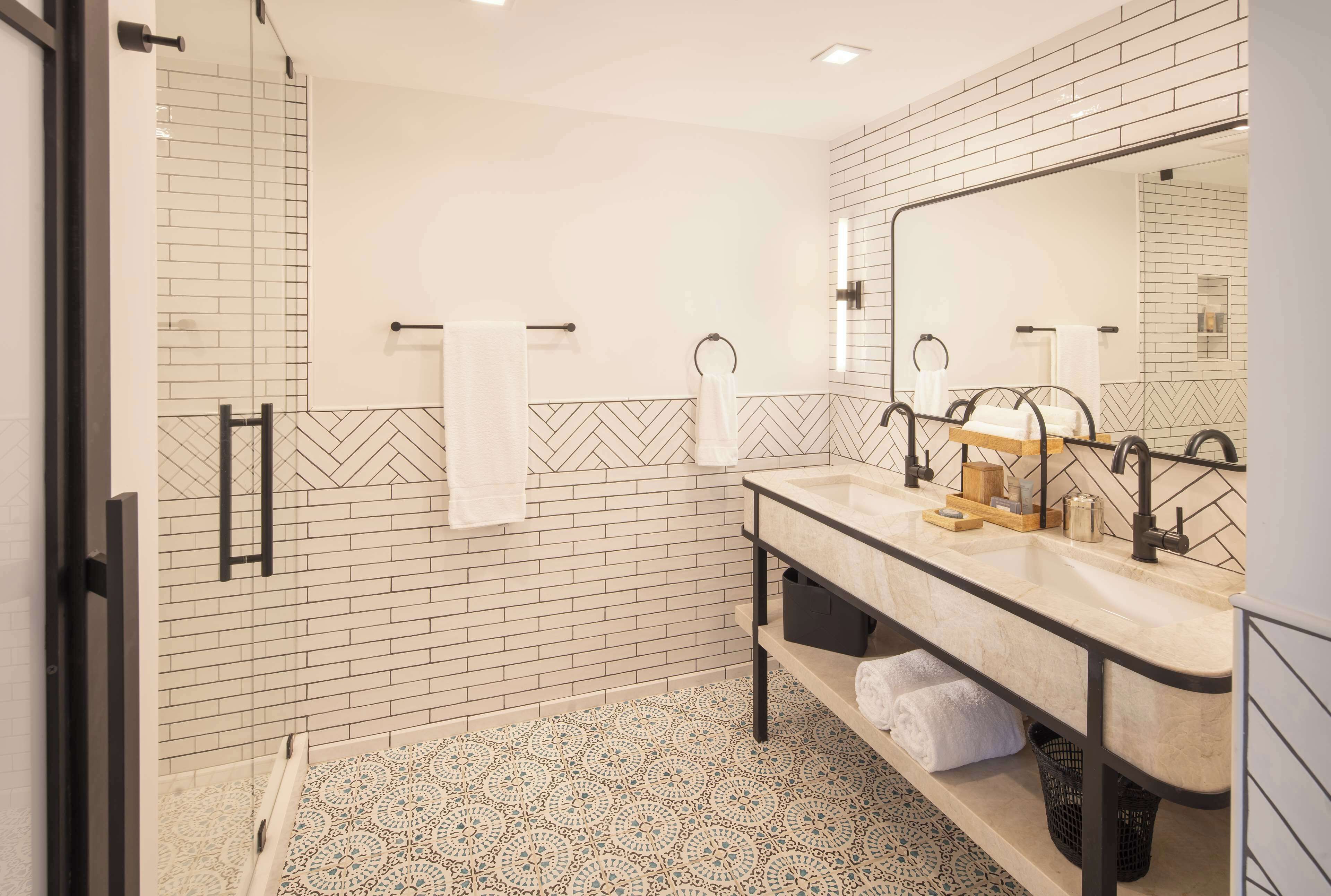 Un baño moderno con un espejo grande, dos lavamanos y una zona de ducha.