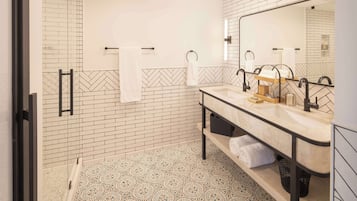 Un baño moderno con un espejo grande, dos lavamanos y una zona de ducha.