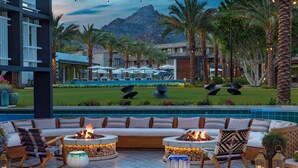 A modern outdoor seating area with a fire pit, lounge chairs, and a pool view. - Arizona Biltmore, LXR Hotels & Resorts (Phoenix)