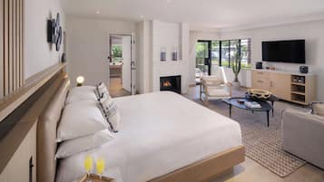 Une chambre d’hôtel moderne dotée d’un grand lit, d’une cheminée, d’une télévision et d’un balcon avec vue.