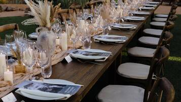 A long wooden table set for a formal event with candles, glassware, and menus.