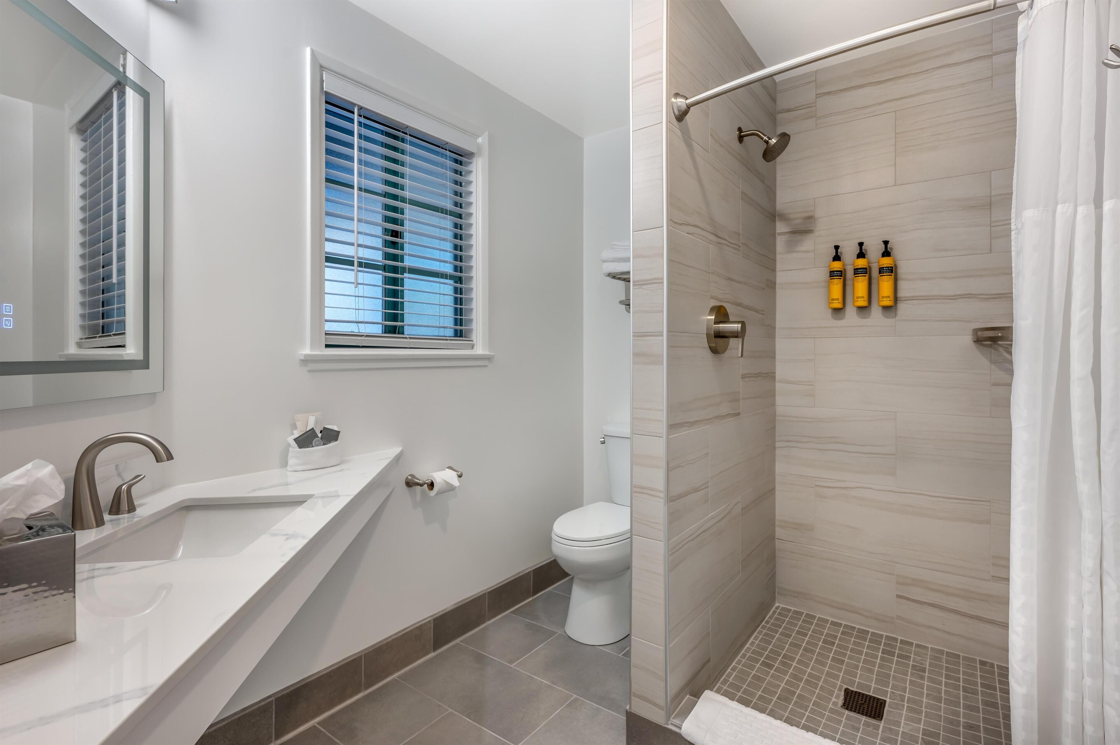 Un bany modern amb un lavabo, vàter i plat de dutxa.