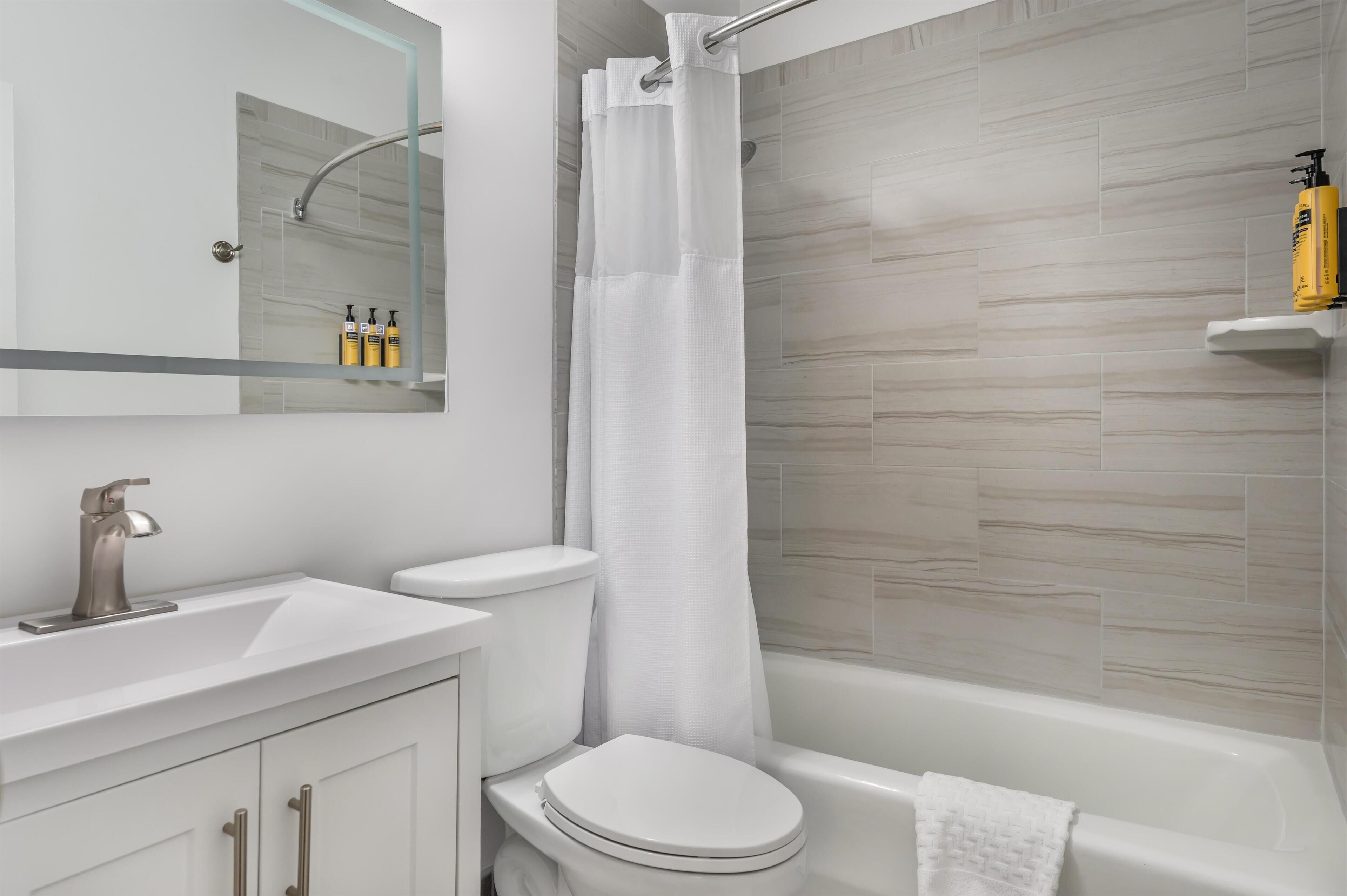 A modern bathroom with a white sink, toilet, and bathtub.