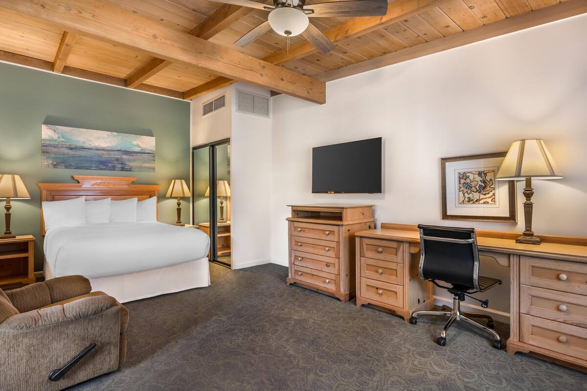 Une chambre d’hôtel équipée d’un lit, d’un bureau, d’une chaise et ornée d’œuvres d’art sur les murs.