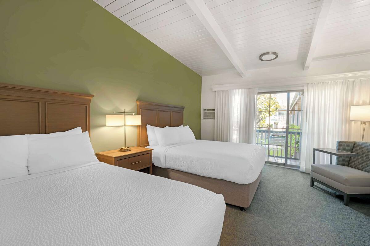 Une chambre d’hôtel avec deux lits, un canapé, une lampe et une vue sur l’extérieur.