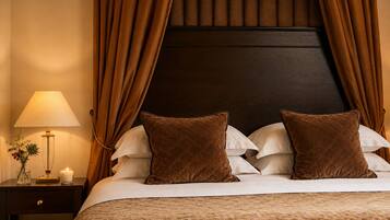 A neatly made bed with brown pillows, a bedside table with a lamp and a candle, and a dark headboard.