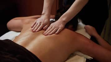 A massage therapy session with a person lying face down on a massage table.