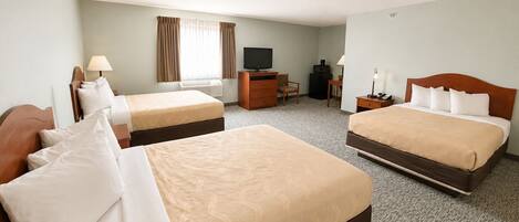 A hotel room with two beds, a desk, a television, and a chair.