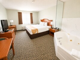 Une chambre d’hôtel équipée d’un lit, d’un bureau, d’une télévision, d’une lampe de bureau, d’un téléphone et d’une baignoire.