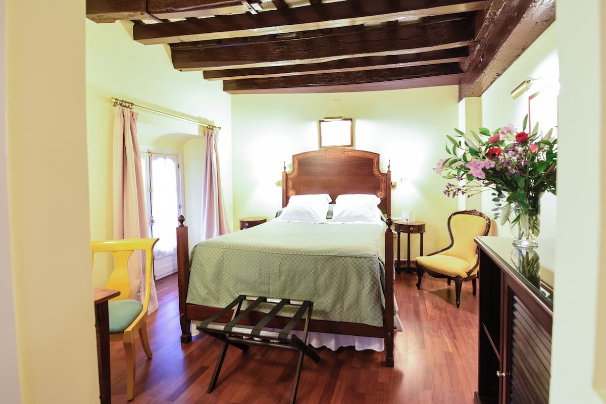 A bedroom with a wooden bed, a chair, a small table, and a nightstand.