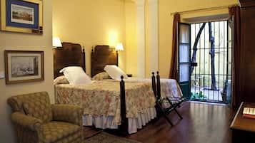 Un dormitorio con cama, una silla, un escritorio y una ventana con cortinas.