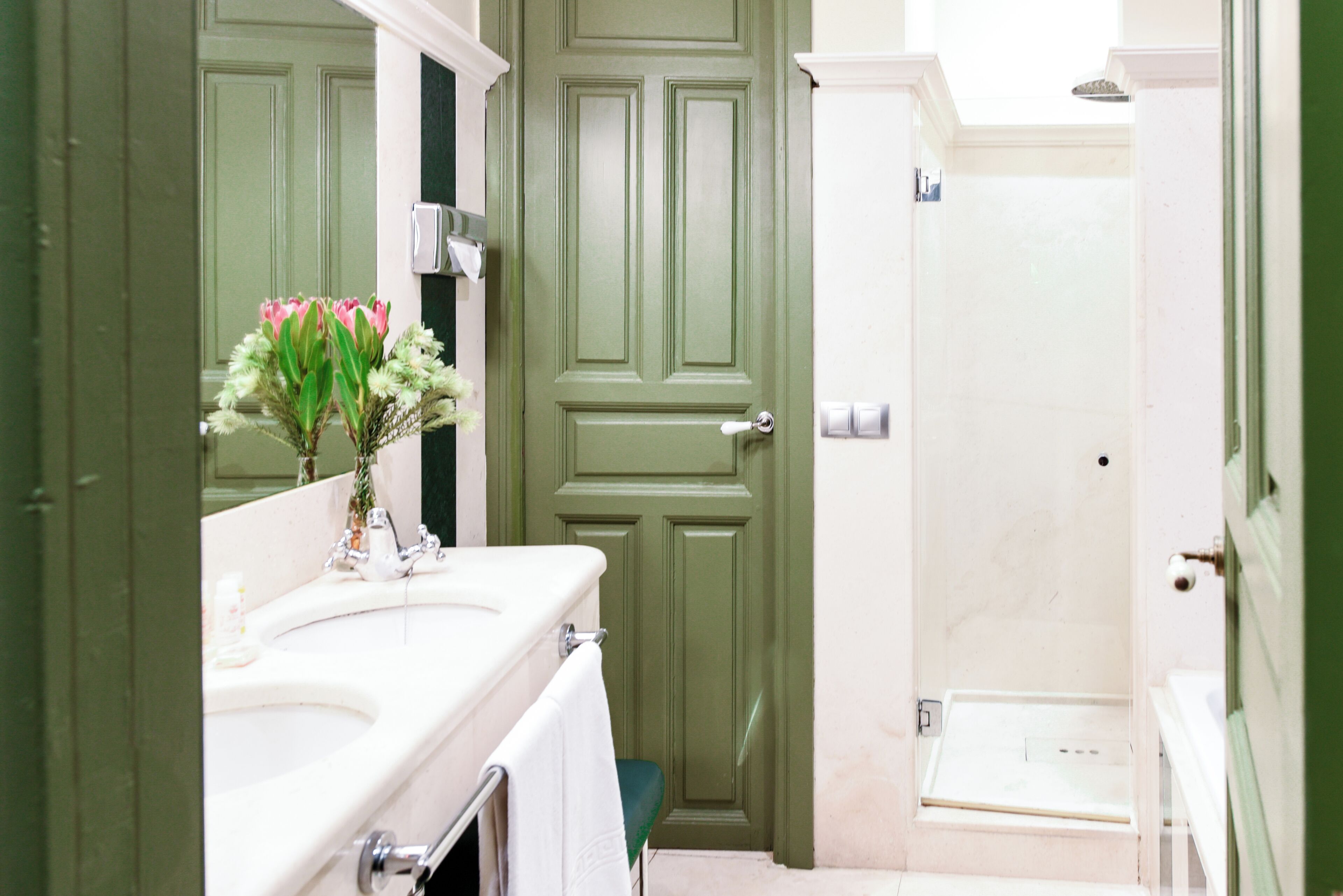 A bathroom with a green door, a white sink, and a mirror.
