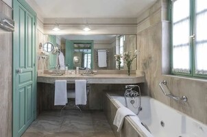 A bathroom with a bathtub, a vanity with a mirror, and a towel rack.