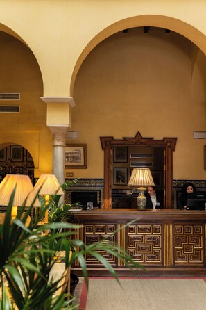 Un espace d’accueil agrémenté d’une colonne en marbre, d’un comptoir de réception et d’une cheminée.