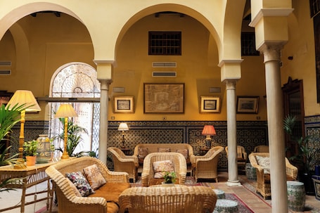 A lobby with a central seating area, columns, and a patterned wall.. Las Casas de la Judería, Sevilla Historic City Center