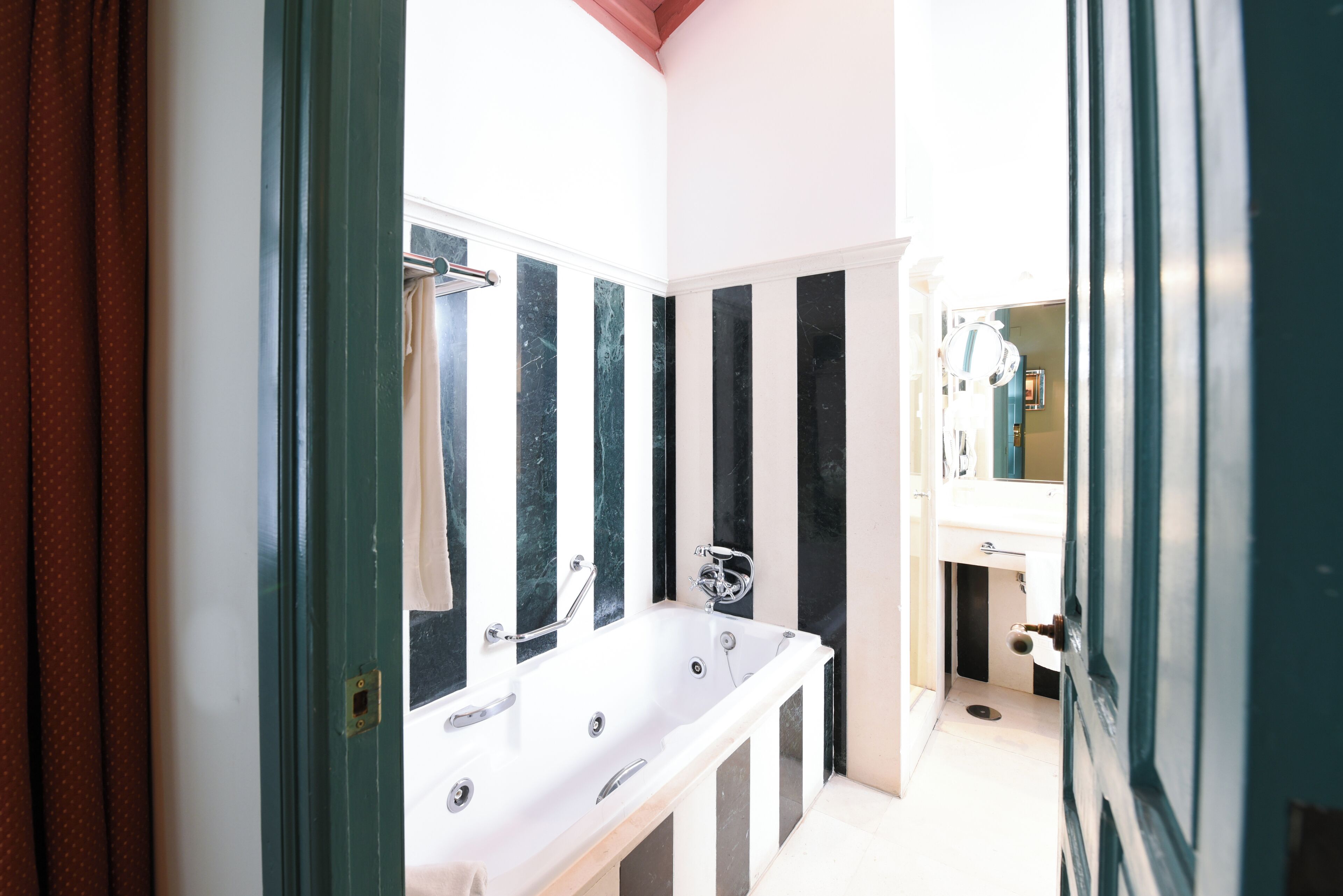 Un baño con una bañera blanca, un espejo y un lavabo.
