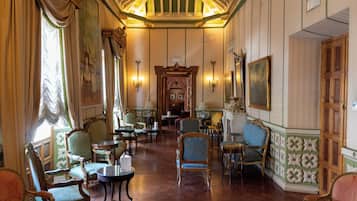 Una habitación con muebles ornamentados, una araña y un cuadro grande en la pared.