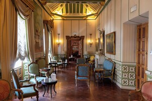 Una habitación con muebles ornamentados, una araña y un cuadro grande en la pared.