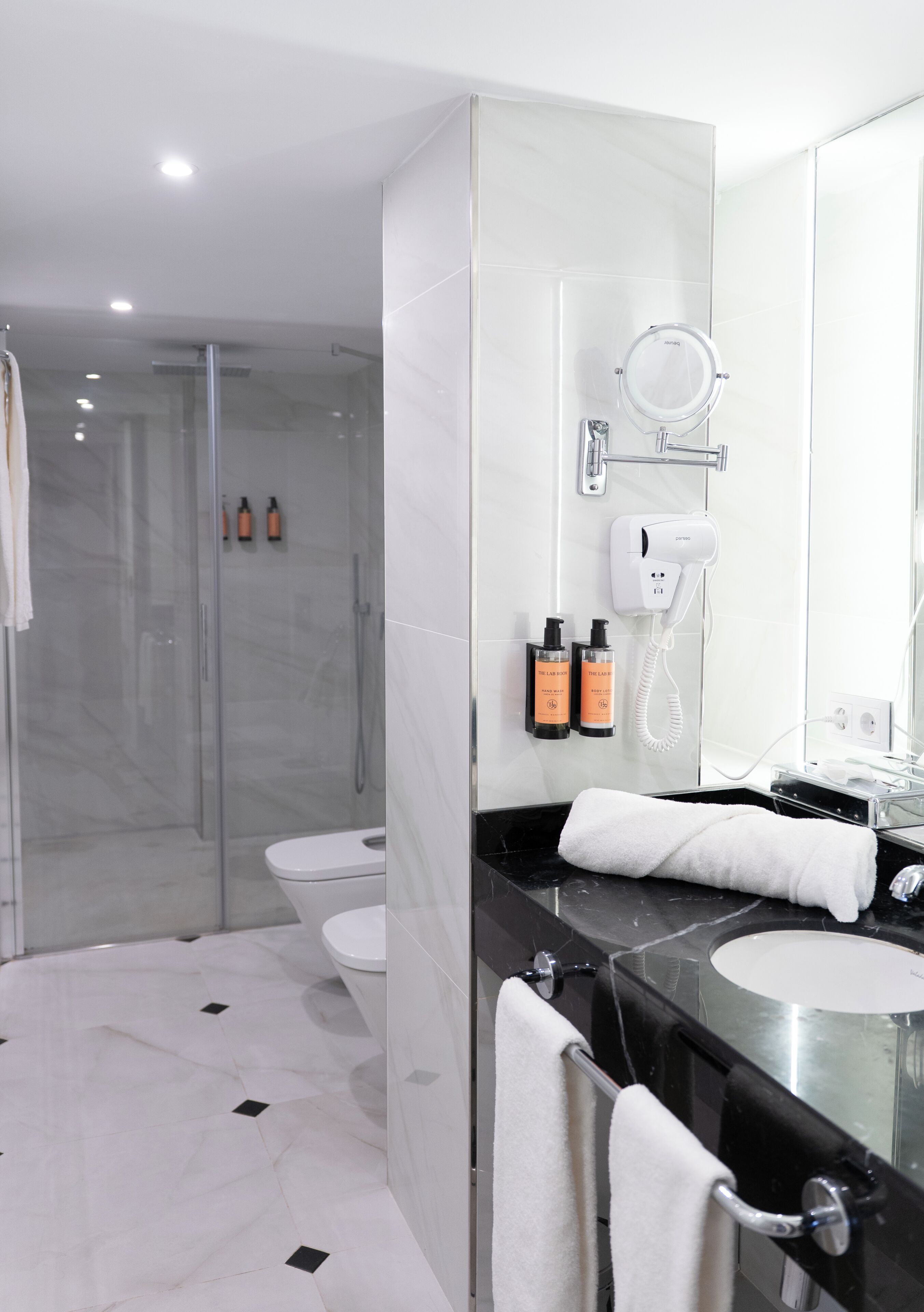 A modern bathroom with a glass shower enclosure, a vanity with a black countertop, and a large mirror.