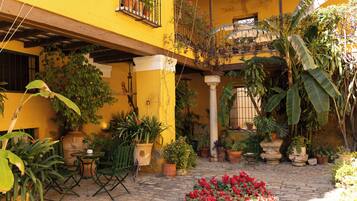 Un patio con plantas en macetas, una mesita y sillas.