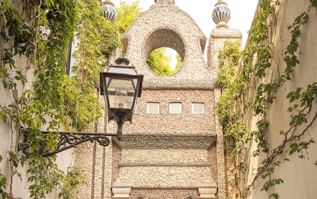 A narrow alleyway with a stone archway, potted plants, and a hanging lantern.