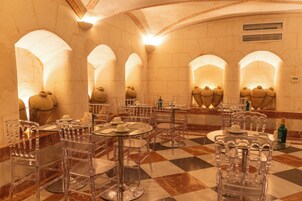Un restaurante con sillas y mesas de vidrio transparente, suelo de mármol y techos abovedados.