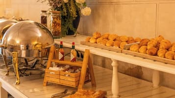 Montaje de bufé con diferentes alimentos, un arreglo floral y una estación de bufé cubierta con una cúpula metálica.