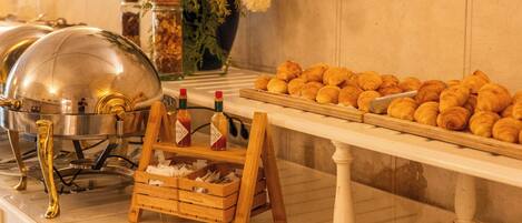 A buffet setup with various food items, a flower arrangement, and a buffet station with a metal dome cover.
