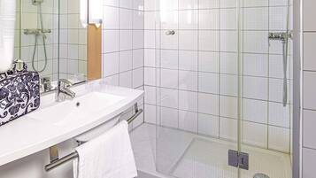 Ein Badezimmer mit Dusche, Waschbecken und Spiegel.