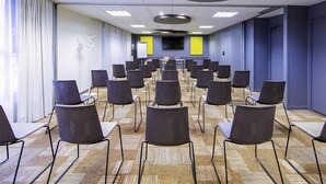 A conference room with rows of chairs, a whiteboard, and a projector screen. - ibis Mulhouse Centre Filature (Mulhouse)
