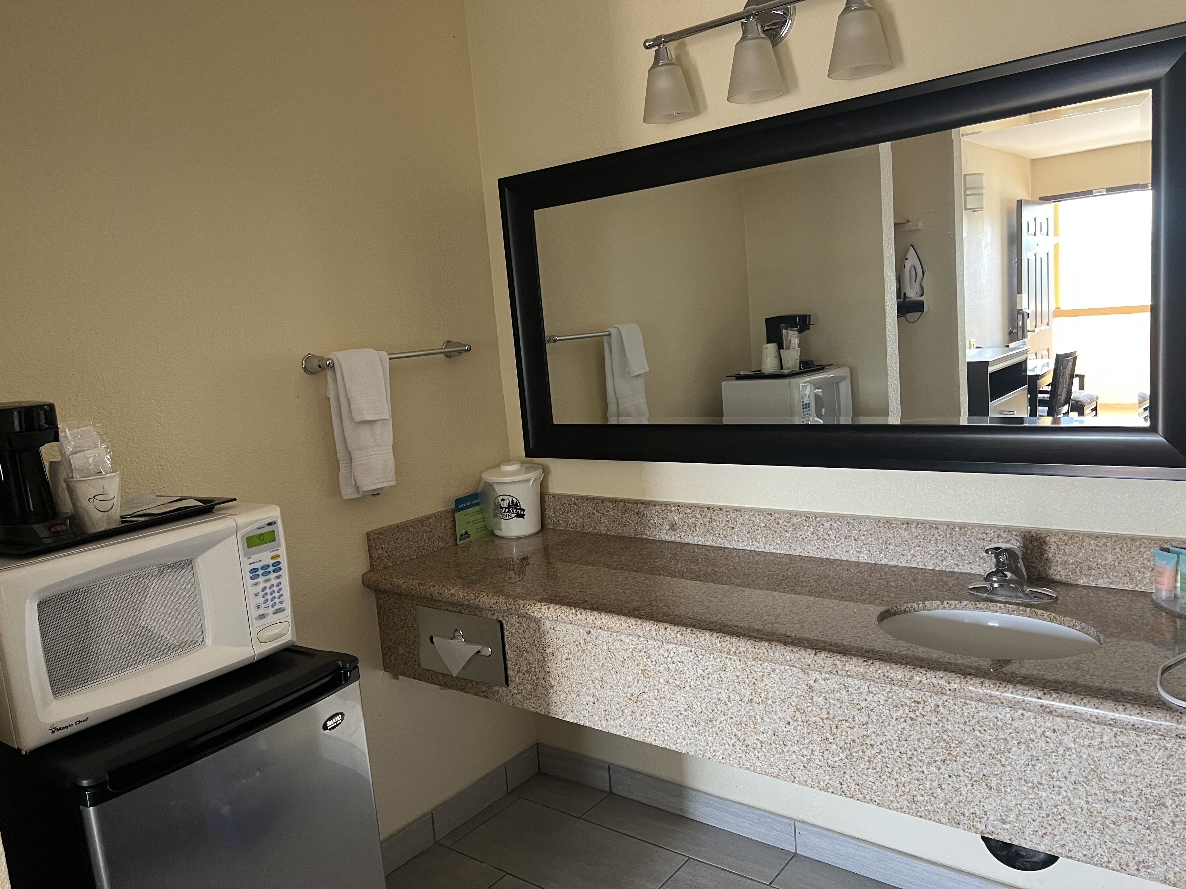 A compact bathroom with a microwave, coffee maker, and a sink.