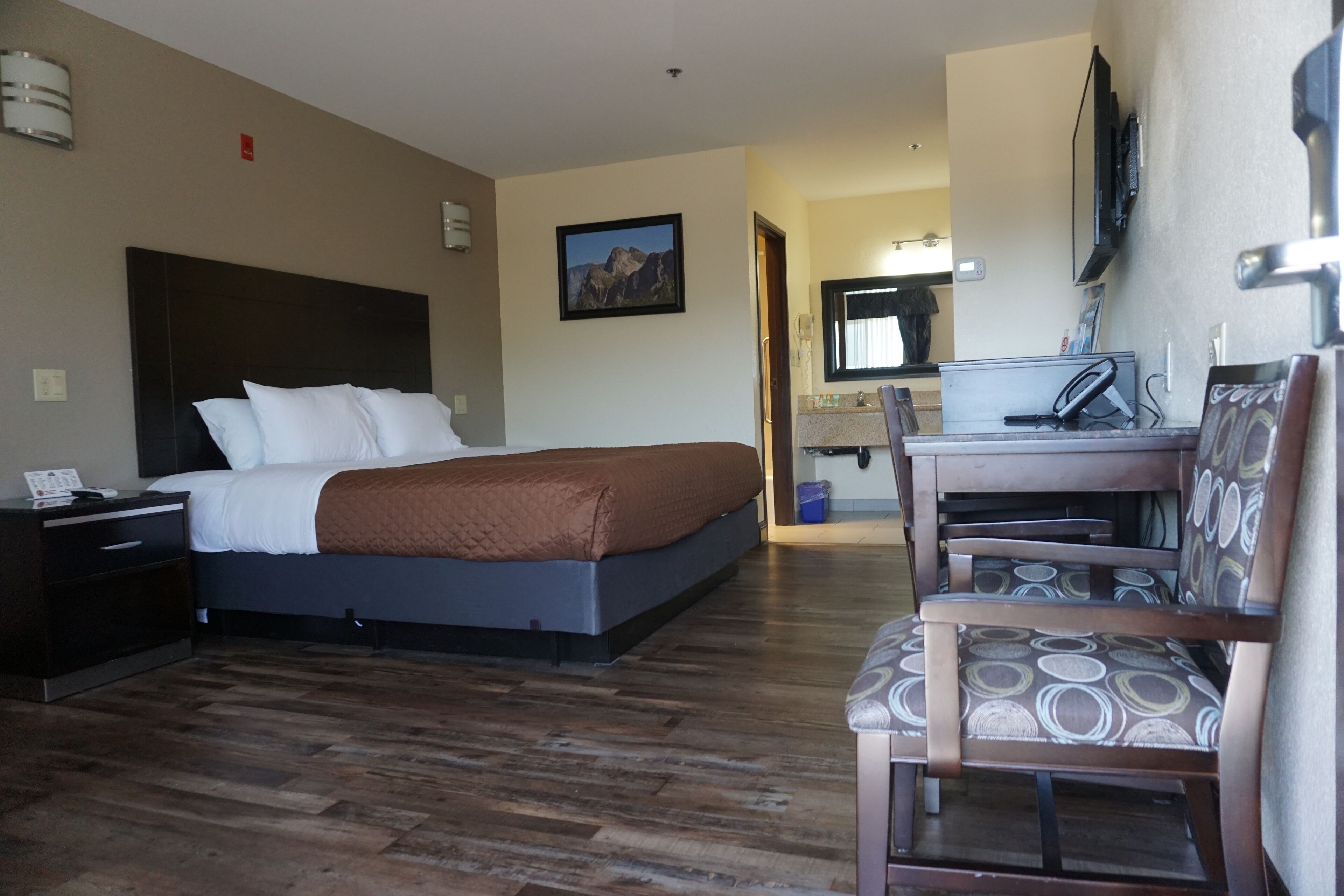 Een hotelkamer met een bed, een bureau, een stoel, een televisie en een badkamer in de achtergrond.