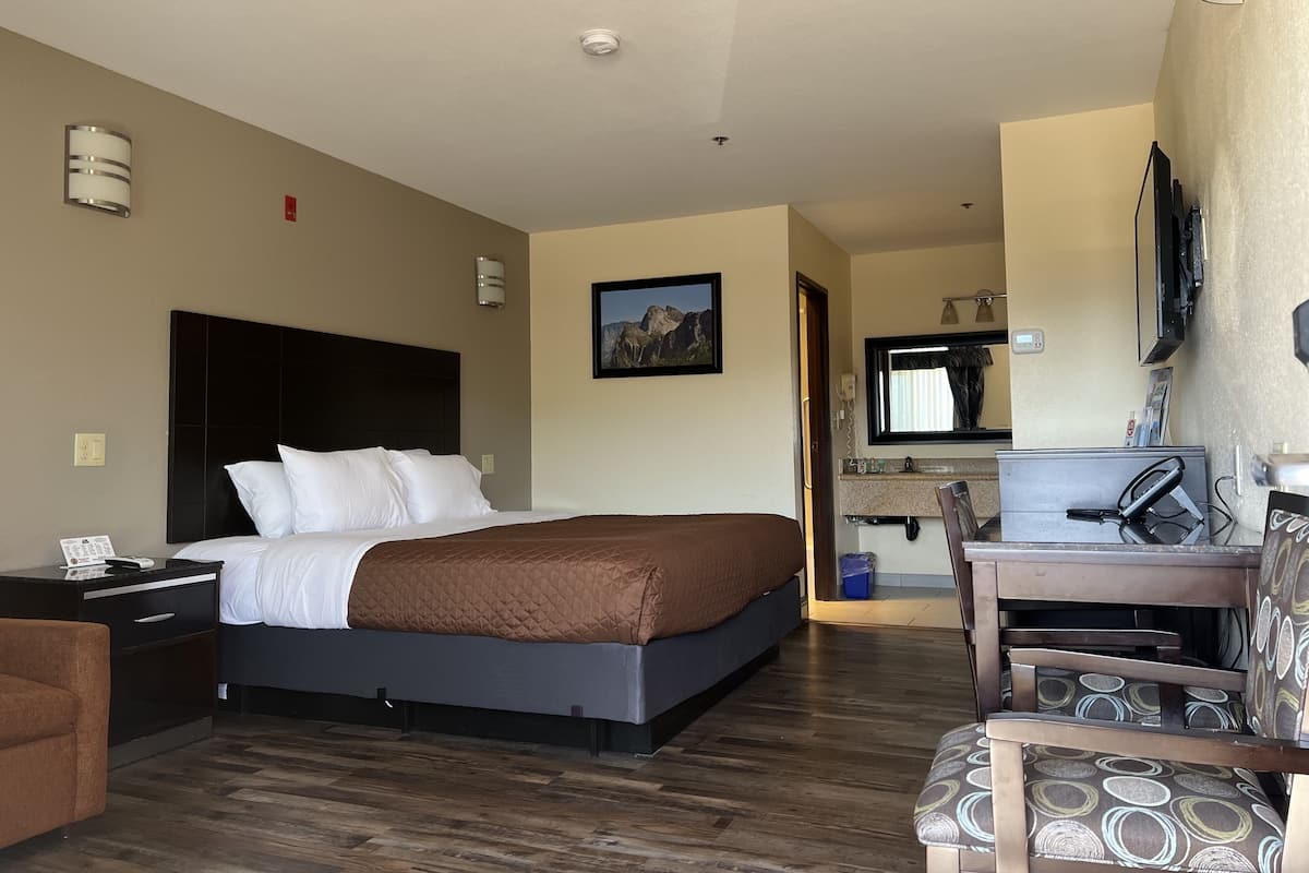 A hotel room with a bed, a desk with a computer, a chair, and a television.