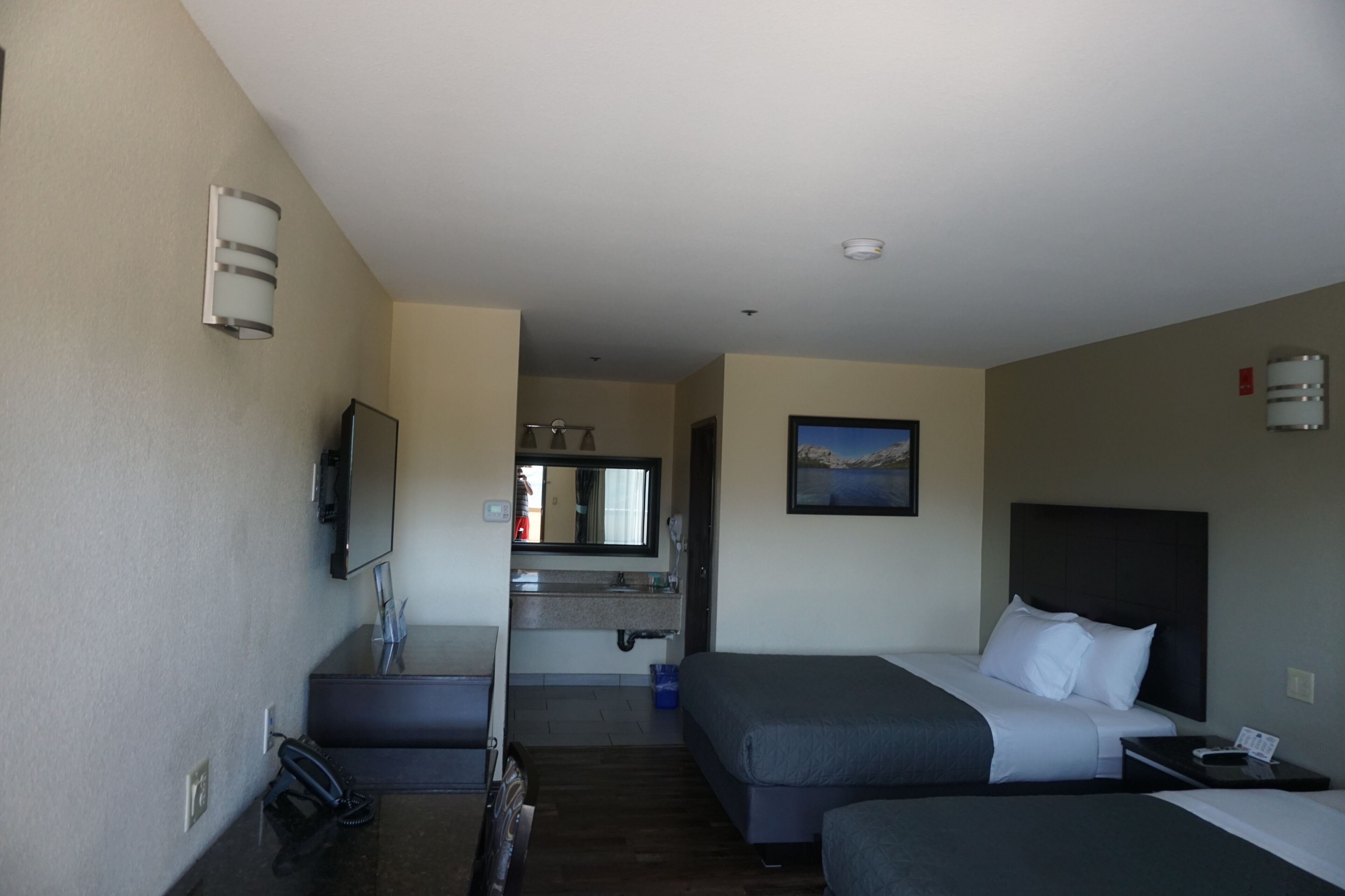 A hotel room with two beds, a bathroom, and a TV.