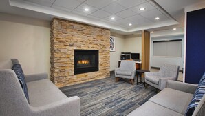 A modern lounge area with a stone fireplace, comfortable seating, and a flat-screen TV. - Holiday Inn Express Sault Ste. Marie by IHG (Sault Ste. Marie)