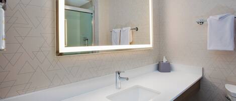 A modern bathroom with a large mirror, a sink, and a toilet.