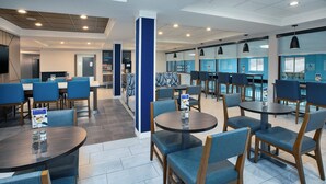 A modern hotel lobby with multiple seating areas, including round tables and chairs, and a large pillar. - Holiday Inn Express Sault Ste. Marie by IHG (Sault Ste. Marie)