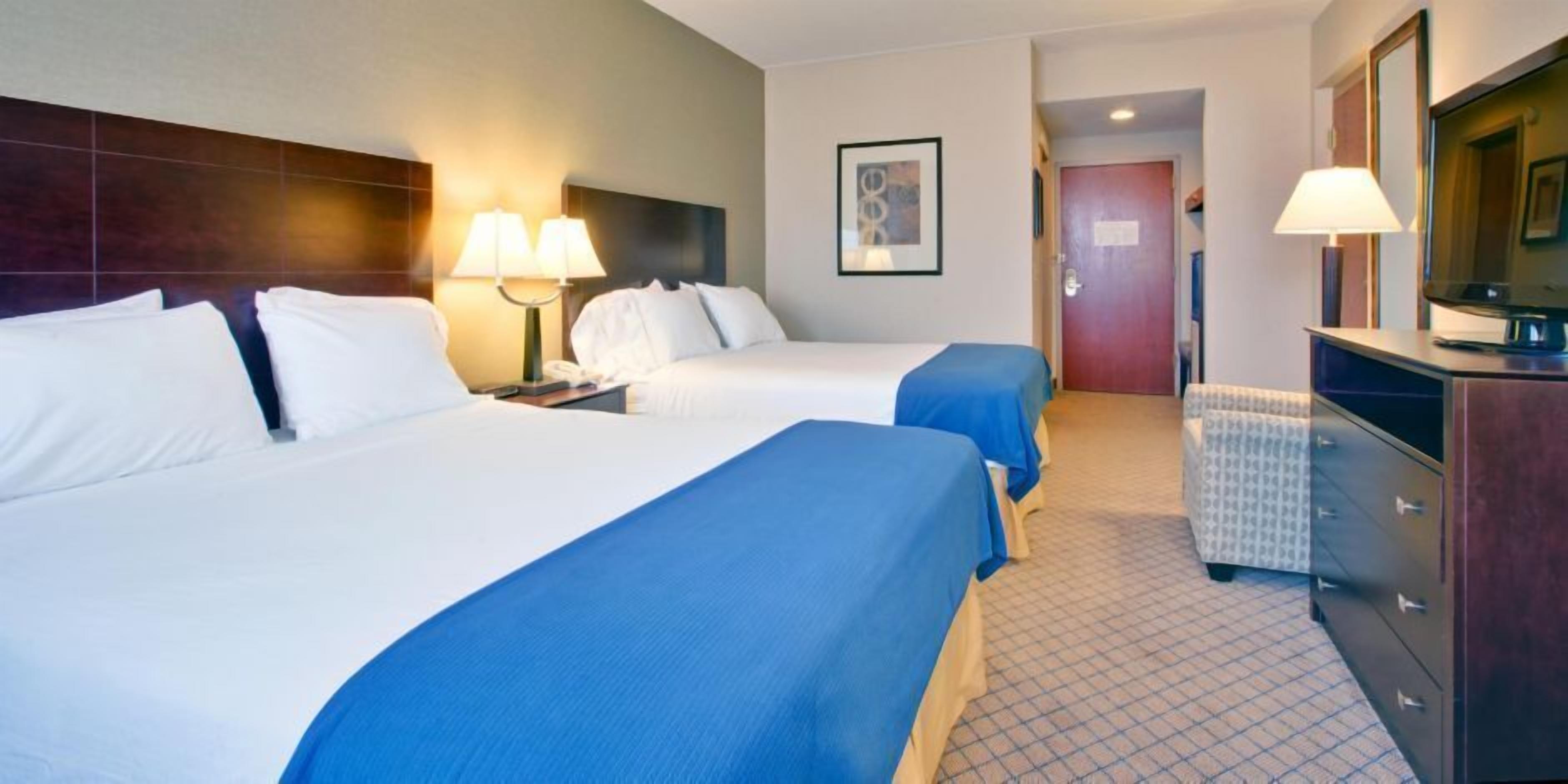 Ein Hotelzimmer mit zwei Betten, einem Schreibtisch, einem Schminktisch und einem Fernseher.