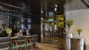 Un hall d’hôtel moderne comprenant un comptoir d’accueil, un espace salon et des plantes décoratives.