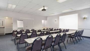 A conference room with a long table, chairs, a projector screen, and a whiteboard.