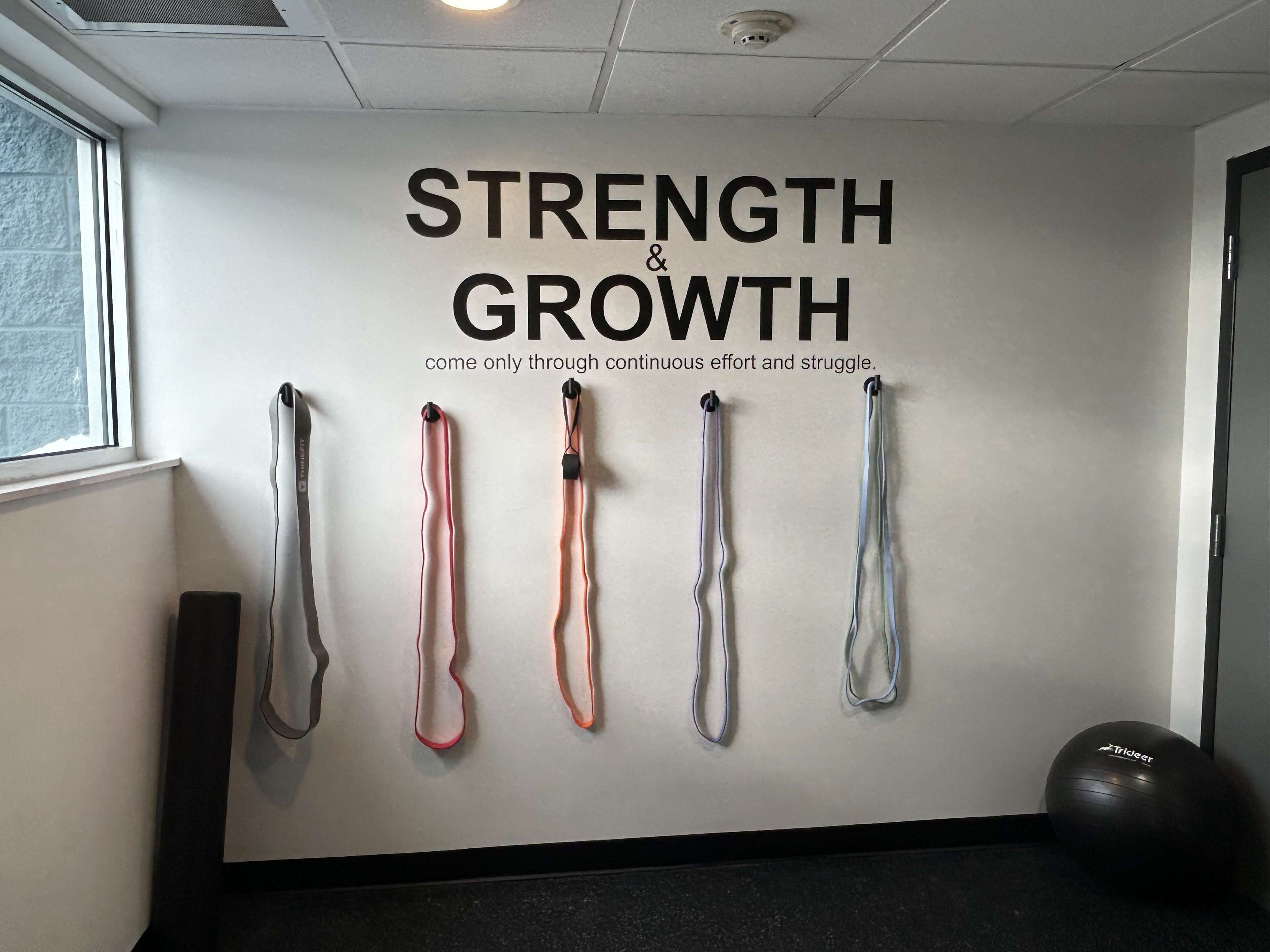 A wall with motivational text and resistance bands.