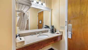 Un baño de hotel con lavamanos, espejo, perchero para toallas y cartel de privacidad.