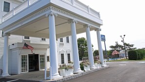 A white building with a covered entrance and columns, an American flag, and a sign reading "Best Western."