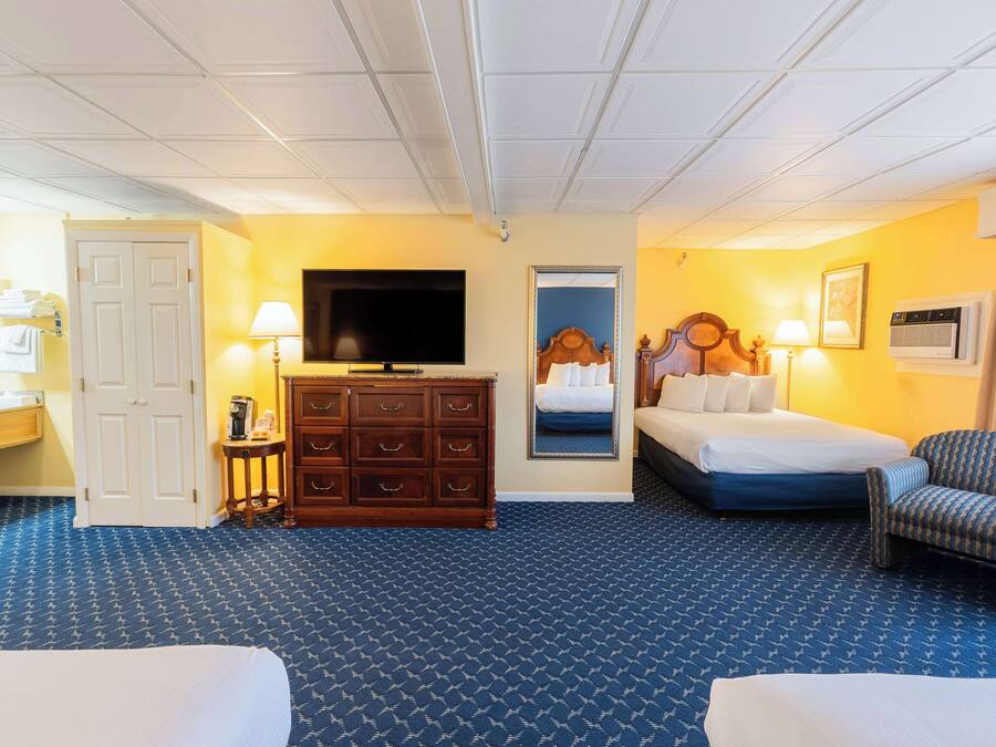 A hotel room with a bed, a dresser, a television, a chair, and a bathroom door.