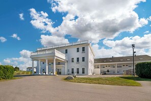 A large white building with a covered porch and multiple windows.